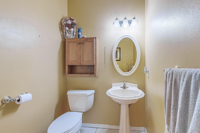 half bathroom featuring tile patterned floors, toilet, and baseboards