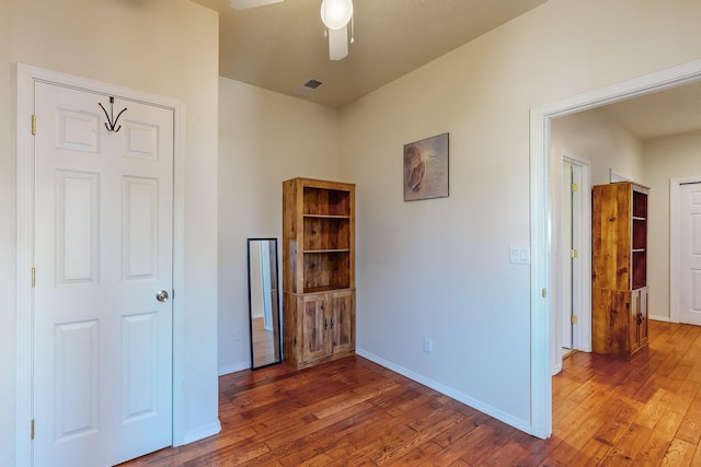 interior space with visible vents, baseboards, wood-type flooring, and ceiling fan