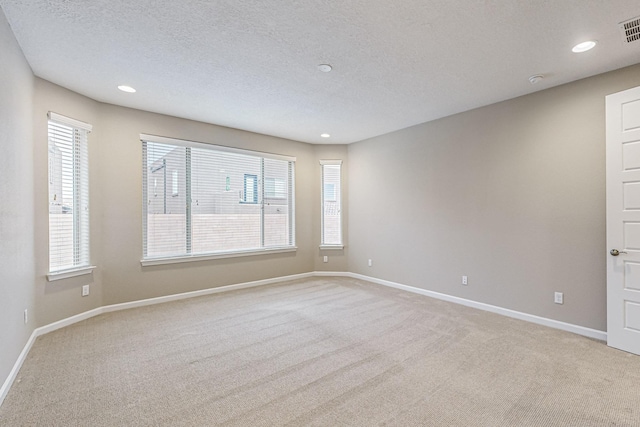 spare room featuring baseboards, visible vents, light colored carpet, a textured ceiling, and recessed lighting