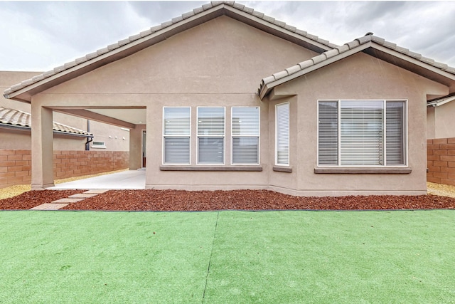 rear view of house featuring a patio, fence, a tiled roof, and stucco siding