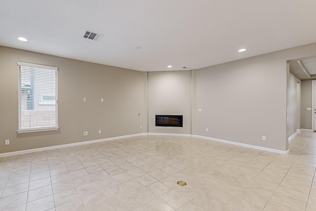 unfurnished living room with light tile patterned floors, recessed lighting, visible vents, a glass covered fireplace, and baseboards