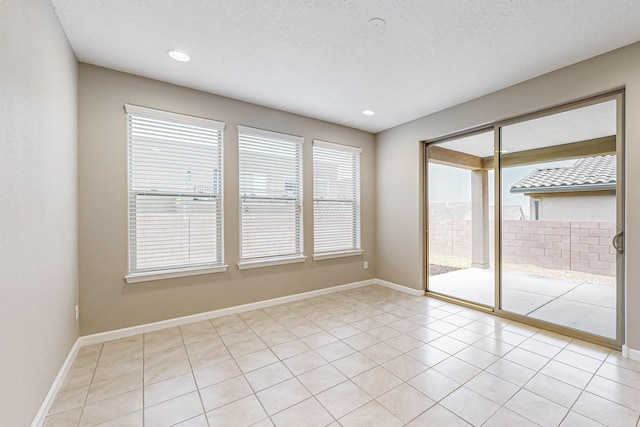 empty room featuring baseboards, a textured ceiling, and recessed lighting