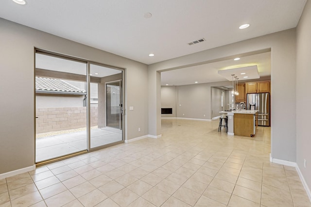 unfurnished living room featuring recessed lighting, a sink, visible vents, and baseboards