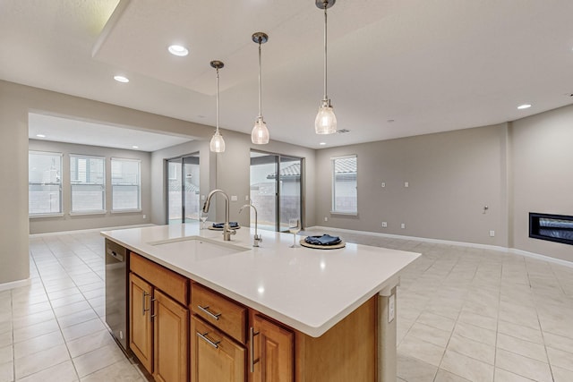 kitchen with open floor plan, light countertops, hanging light fixtures, and a sink