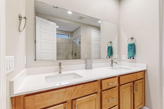 full bath featuring double vanity, a sink, visible vents, and a shower stall