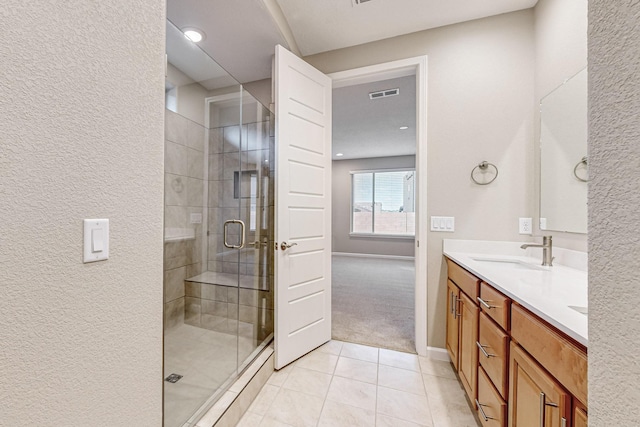 full bathroom featuring tile patterned flooring, a sink, visible vents, a shower stall, and double vanity