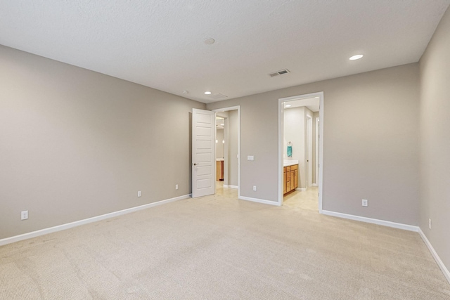 spare room with light carpet, baseboards, visible vents, and a textured ceiling