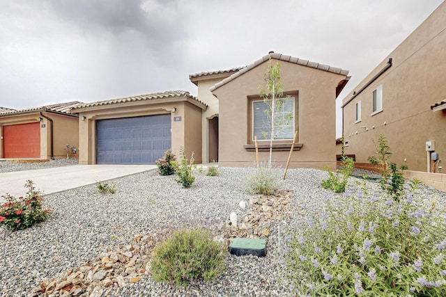 mediterranean / spanish home with a garage, driveway, a tile roof, and stucco siding