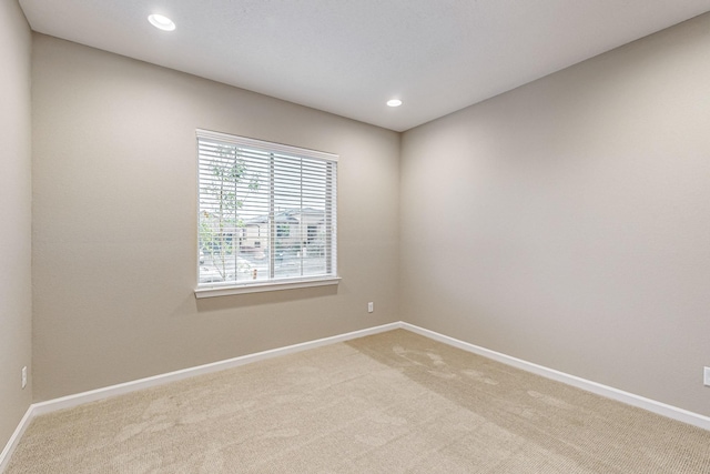 spare room featuring recessed lighting, baseboards, and light colored carpet