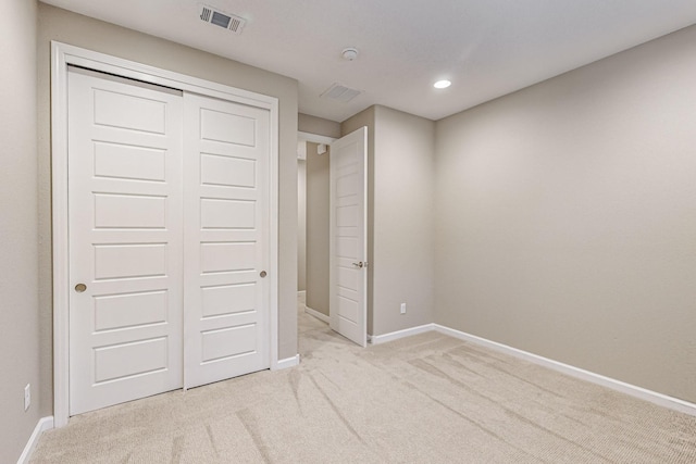 unfurnished bedroom featuring light carpet, a closet, visible vents, and baseboards