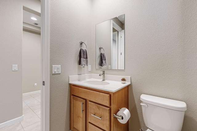 bathroom featuring toilet, a textured wall, tile patterned flooring, and vanity