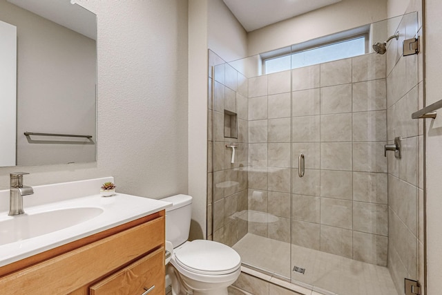 bathroom featuring toilet, a stall shower, and vanity