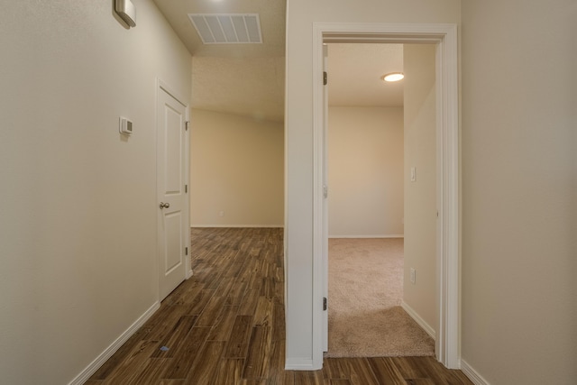 hallway featuring dark wood-style floors, visible vents, and baseboards