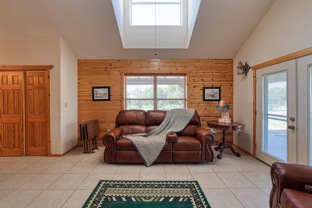 living area featuring wood walls, vaulted ceiling with skylight, french doors, and light tile patterned flooring