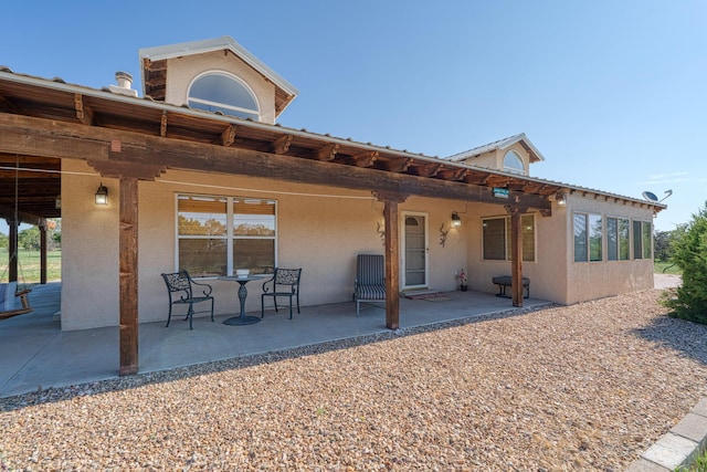 rear view of house featuring a patio area and stucco siding