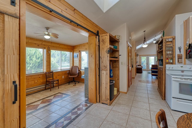 kitchen featuring light tile patterned floors, vaulted ceiling with skylight, wooden walls, electric range, and hanging light fixtures