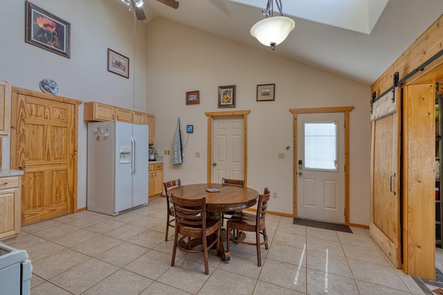 tiled dining room featuring ceiling fan, high vaulted ceiling, and a barn door