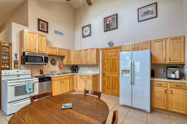 kitchen featuring appliances with stainless steel finishes, high vaulted ceiling, light tile patterned floors, backsplash, and sink