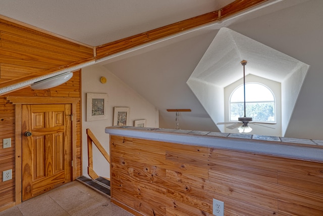 additional living space with ceiling fan, wood walls, and vaulted ceiling