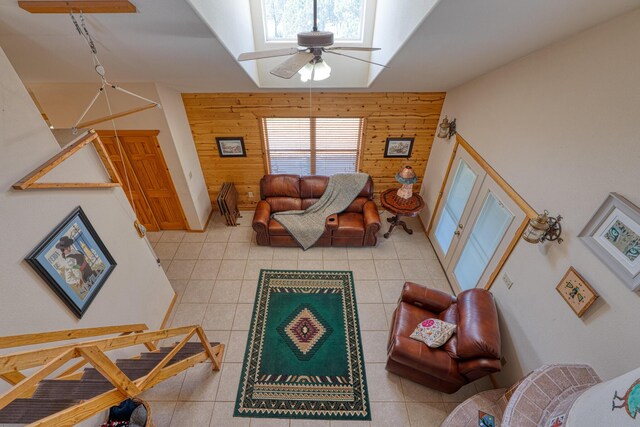 living room featuring ceiling fan, wooden walls, a wealth of natural light, and light tile patterned floors