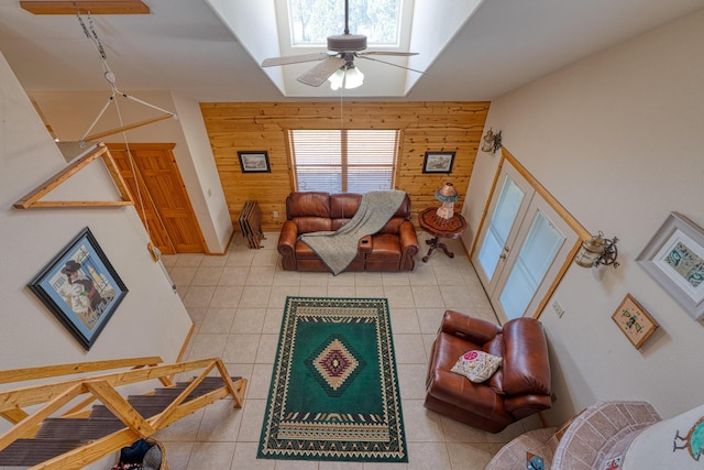 living room featuring ceiling fan, wooden walls, and light tile patterned floors