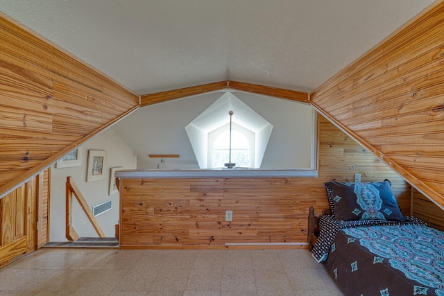 bonus room with lofted ceiling, visible vents, wood walls, and tile patterned floors