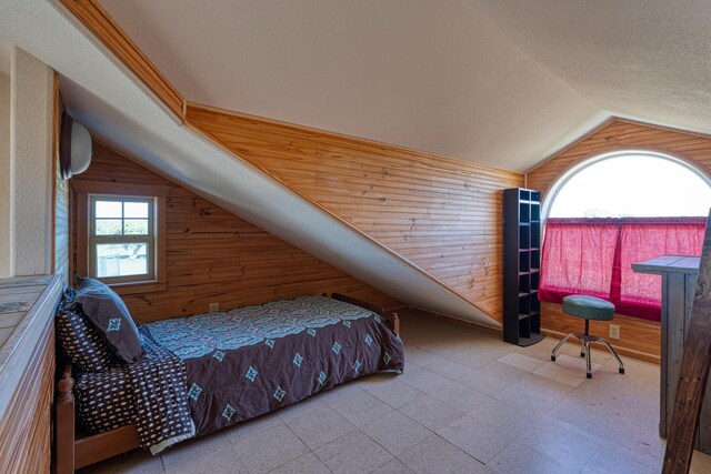 tiled bedroom with a textured ceiling, wooden walls, and lofted ceiling