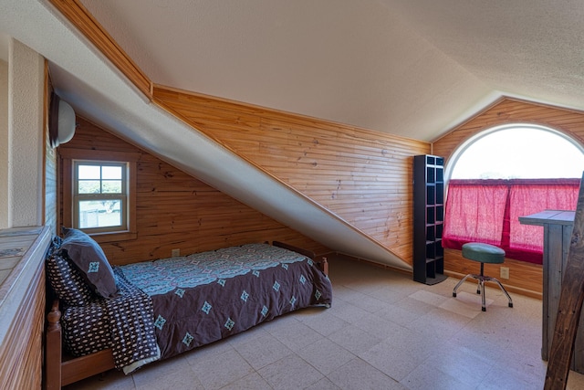 bedroom featuring lofted ceiling, light floors, wood walls, and a textured ceiling