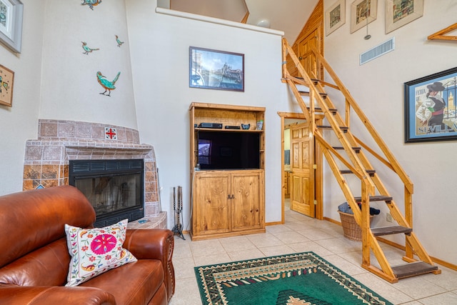 living room featuring high vaulted ceiling, a tile fireplace, and light tile patterned floors