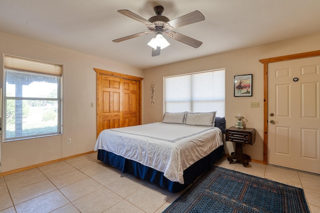 bedroom with light tile patterned floors, ceiling fan, baseboards, and a closet