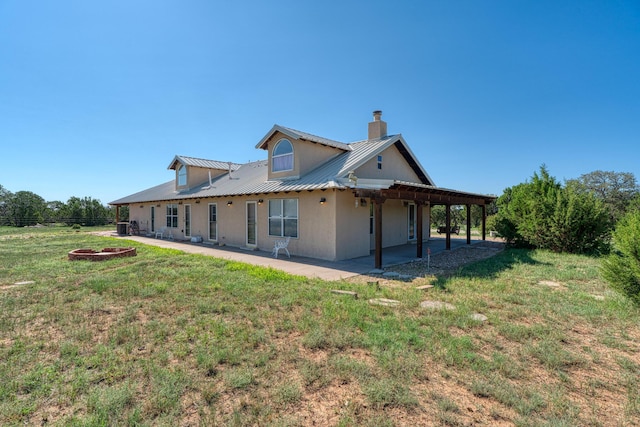 back of property featuring stucco siding, metal roof, a lawn, and a patio