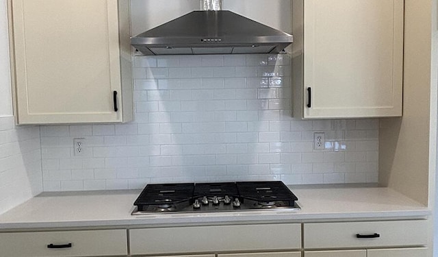 kitchen featuring white cabinets, range hood, backsplash, and stainless steel gas cooktop