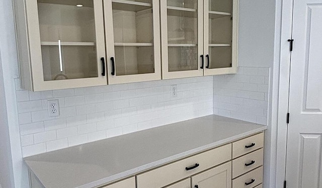 kitchen with white cabinets, glass insert cabinets, backsplash, and light countertops
