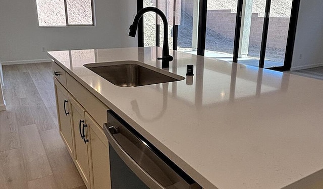 kitchen featuring baseboards, white cabinetry, light wood-style floors, dishwasher, and a sink