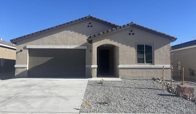 mediterranean / spanish-style house with an attached garage, fence, concrete driveway, a tiled roof, and stucco siding