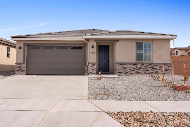 view of front of house featuring stucco siding, an attached garage, stone siding, driveway, and a tiled roof