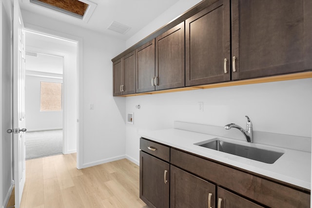 washroom featuring light wood-style flooring, washer hookup, a sink, visible vents, and cabinet space