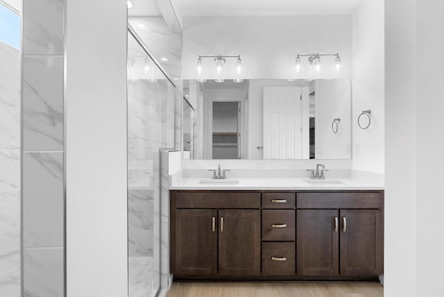 full bath with a sink, a spacious closet, a marble finish shower, and double vanity