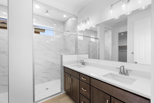 full bath featuring a marble finish shower, a sink, and a walk in closet