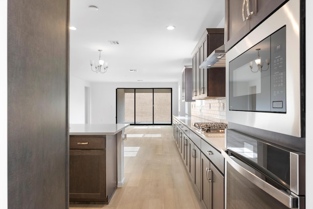 kitchen featuring stainless steel gas stovetop, light countertops, hanging light fixtures, and backsplash