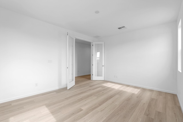 empty room featuring light wood-style flooring, visible vents, and baseboards