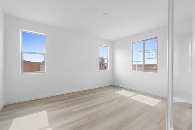 unfurnished room featuring baseboards and light wood finished floors