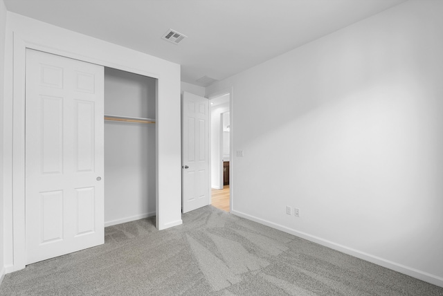 unfurnished bedroom with carpet floors, a closet, visible vents, and baseboards