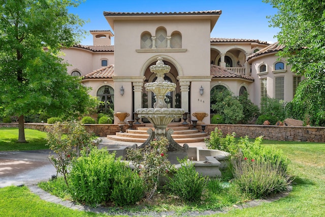 mediterranean / spanish-style home with stucco siding, a tiled roof, and a front lawn