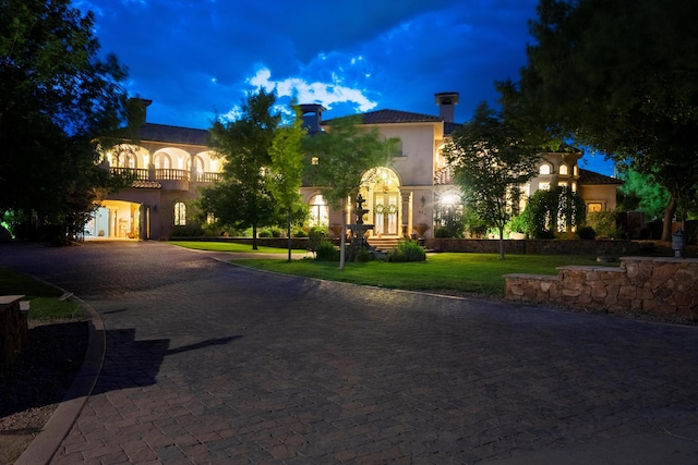 mediterranean / spanish house featuring stucco siding, a front yard, decorative driveway, and a balcony