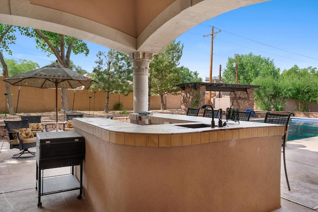 view of patio / terrace featuring a sink, outdoor wet bar, and fence