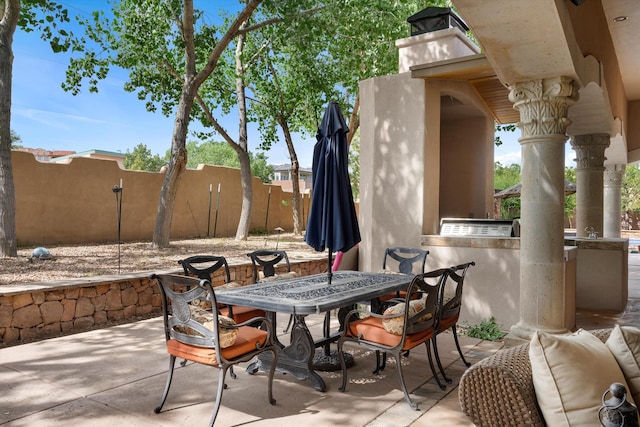 view of patio with an outdoor kitchen, outdoor dining space, and fence