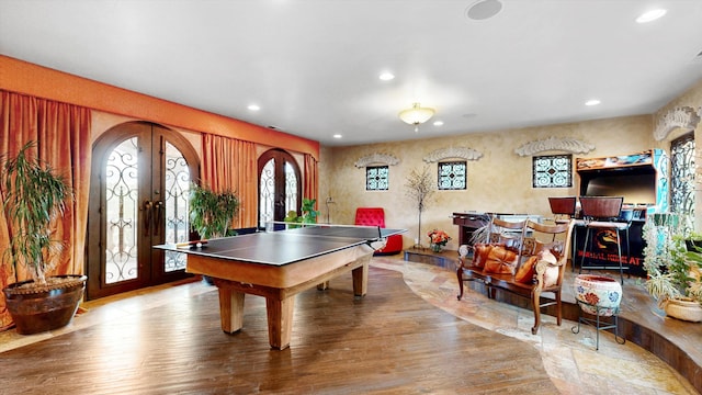 recreation room featuring arched walkways, recessed lighting, french doors, and wood finished floors