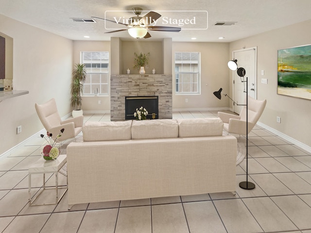 unfurnished living room featuring a stone fireplace, ceiling fan, light tile patterned flooring, and a textured ceiling