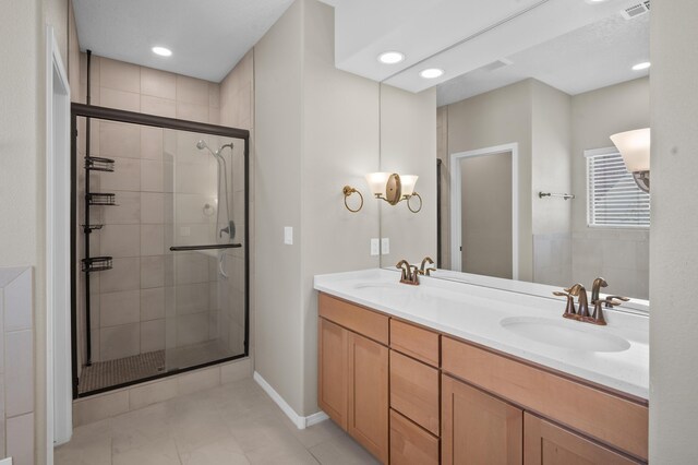 bathroom with tile patterned flooring, a shower with door, and dual bowl vanity